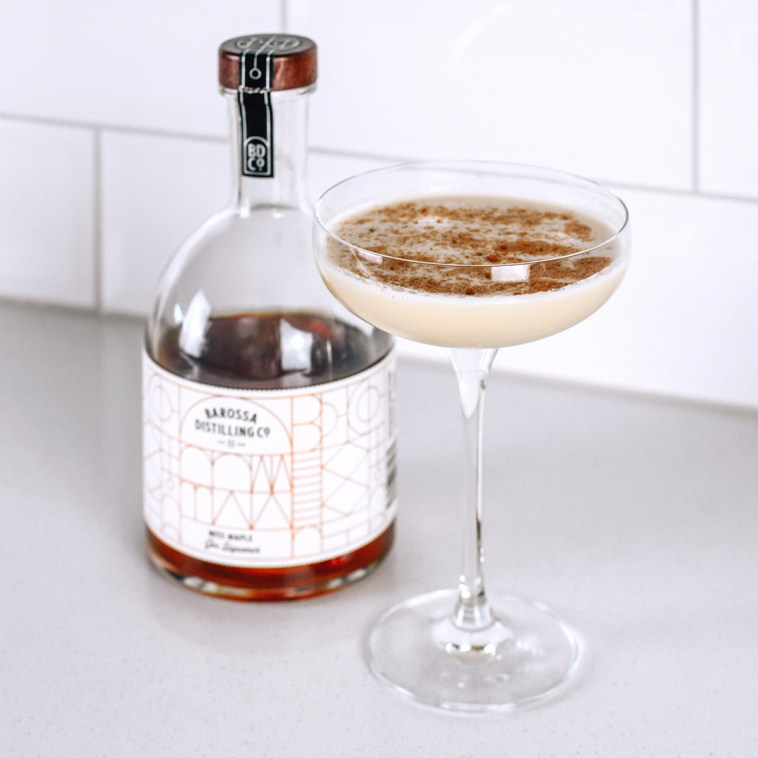 Maple Gin Flip cocktail in coupe glass with a bottle of Miss Maple